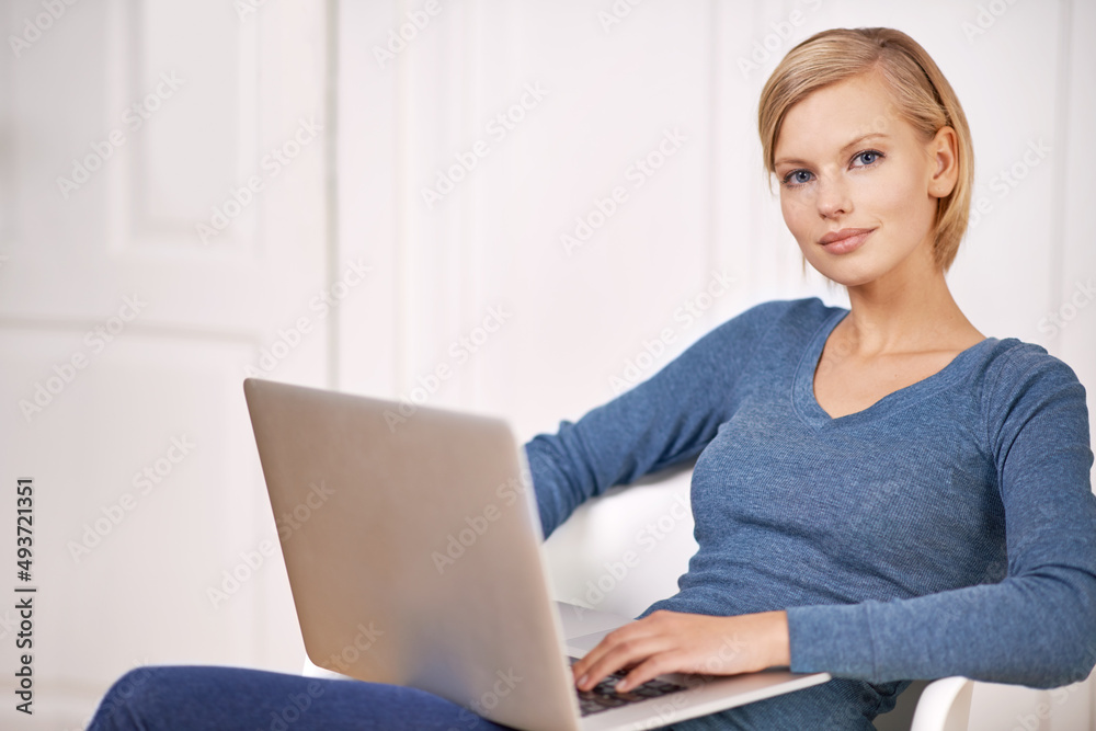 Browsing the news feed. Portrait of a beautiful woman sitting on a chair using a laptop. Browsing the news feed. Portrait of a beautiful woman sitting on a chair using a laptop.