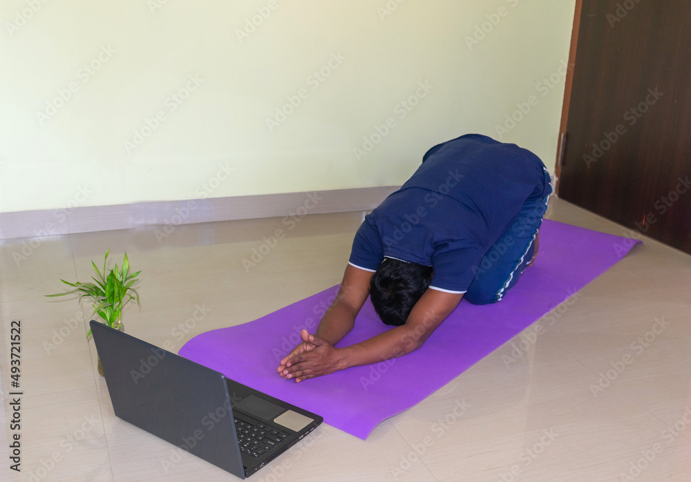 Top view at fit sporty healthy Indian man sitting on a mat in a Yoga