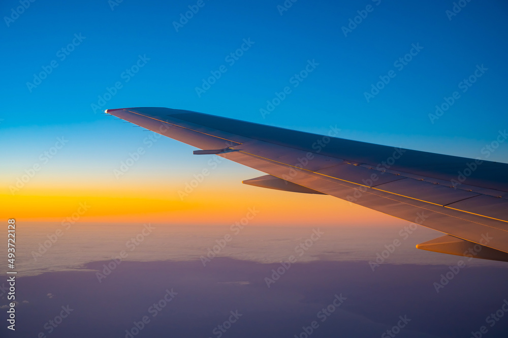 Obraz premium View of the wing of an airplane during flight from the window at sunset.