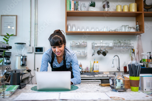 happy woman barista using laptop for take order from customer in coffee shop.
