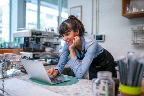 happy woman barista using laptop for take order from customer in coffee shop.