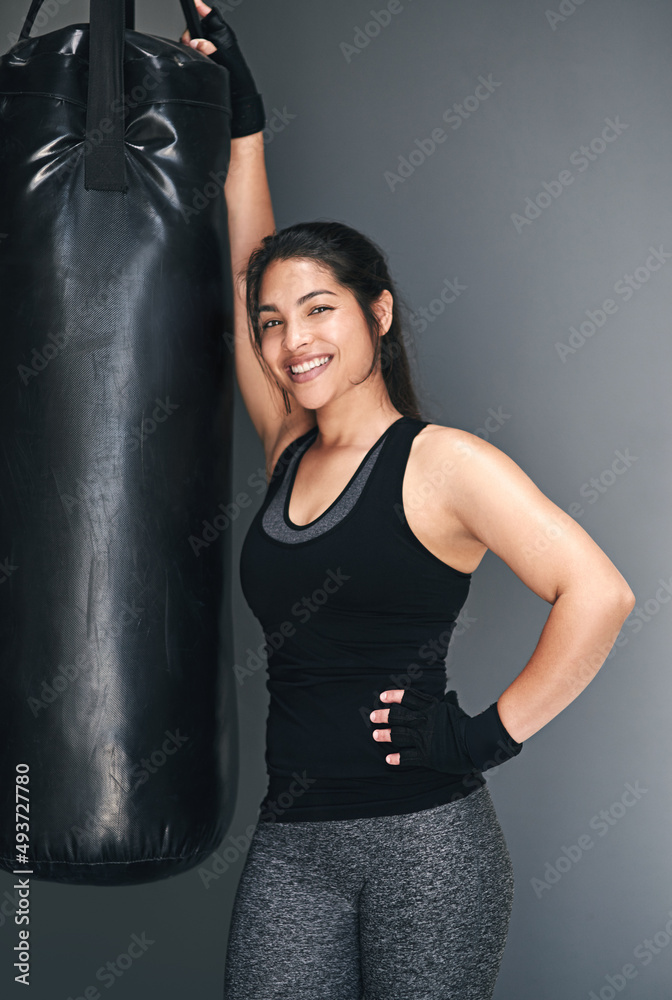 Wanna spot me. Studio shot of a female kickboxer against a gray background.