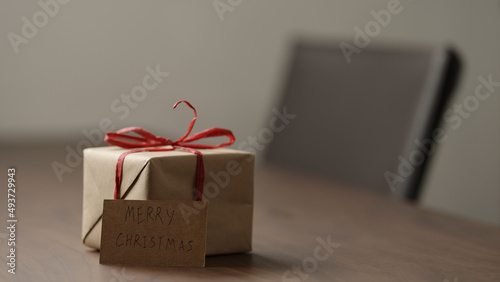 brown paper gift box with red bow on wood table with paper card