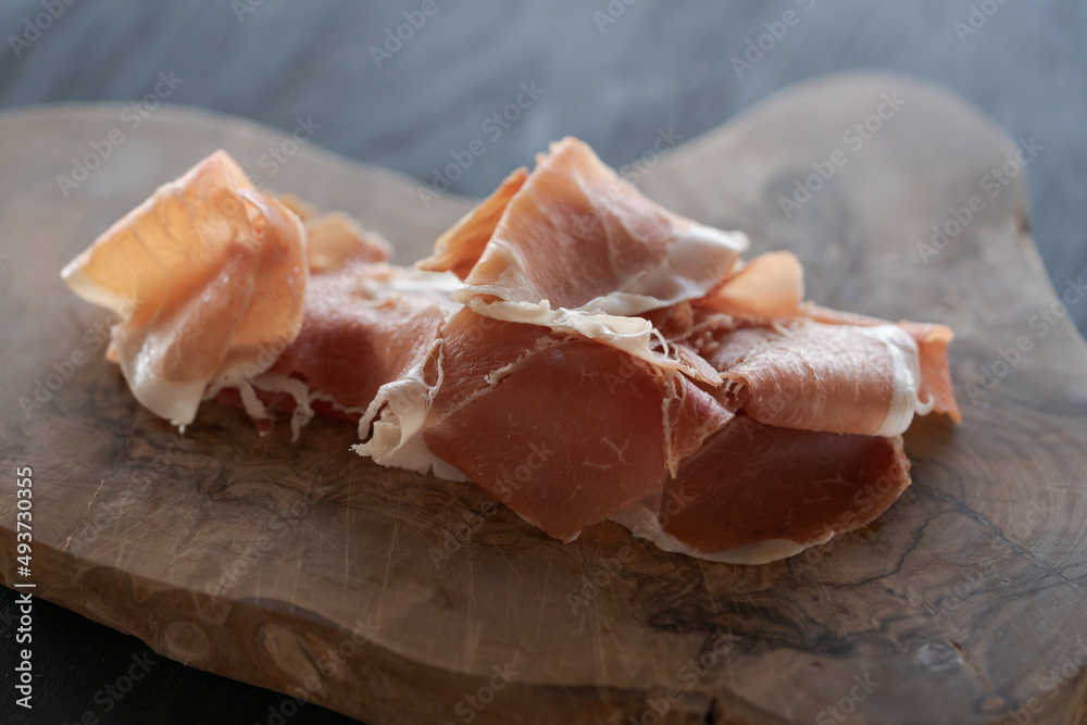 Thin slices of jamon on olive wood board