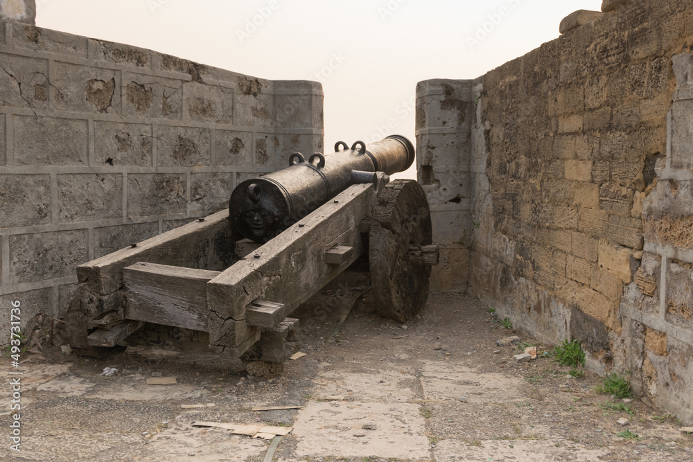 Rear view of a movable sixteenth century Portuguese cannon made of metal with a face design at the back and wooden base. It's located on a bastion of Diu Fort, Diu, India