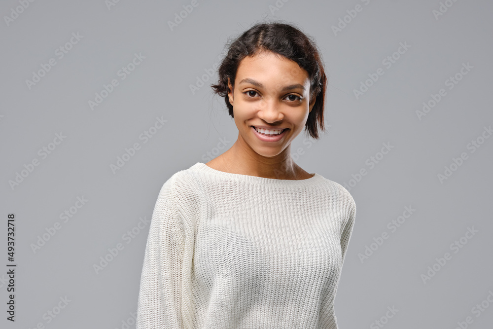 Closeup portrait of young african woman smiling against gray background Closeup portrait of young african woman smiling against gray background