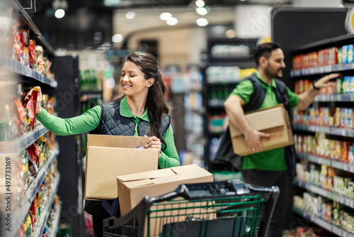 The employees arranging groceries on shelves in supermarket. photo
