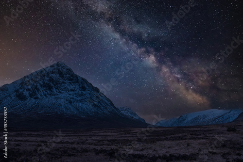 Majestic vibrant Milky Way composite image over landscape of snowcapped Winter mountains in Scotland