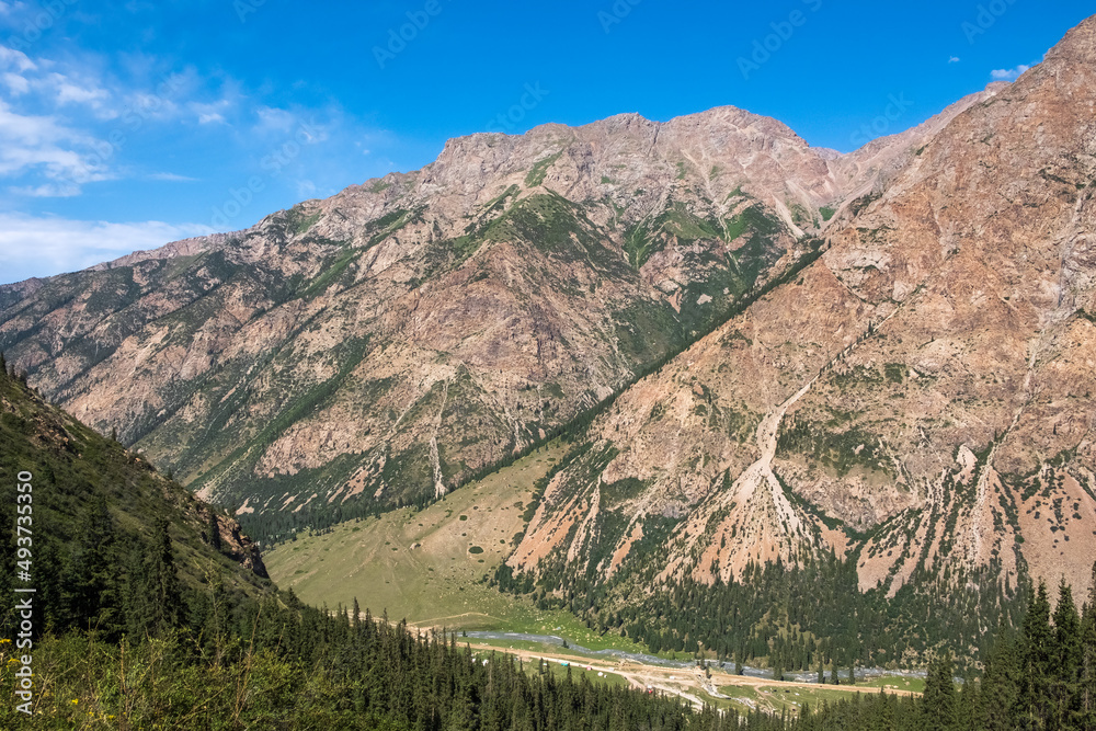 Fototapeta premium Beautiful mountain valley with rocky mountains and sky. Barskoon river mountain gorge. Travel, tourism in Kyrgyzstan concept.