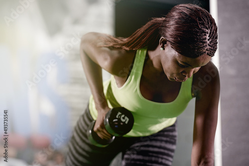 You can never go wrong with strong. Shot of a young woman lifting weights at the gym.