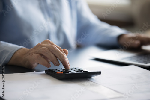 Fotobehang Close up cropped view woman sit at desk use calculator and laptop, calculates domestic expenditures, manage monthly finance, makes household bills payment through e-bank
