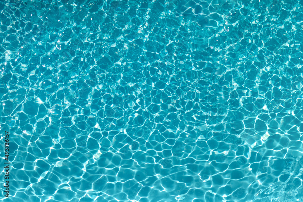 The excitement of the water in the pool. The texture of the surface of the blue pool, the background of the water in the pool with sun glare. copy space.