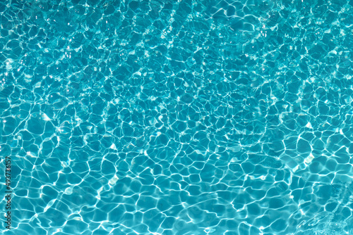 The excitement of the water in the pool. The texture of the surface of the blue pool, the background of the water in the pool with sun glare. copy space.