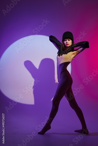 Pretty young female posing on stage spotlight silhouette disco purple background unaltered