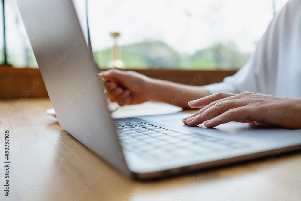 Closeup image of a woman drinking coffee while working on laptop computer Closeup image of a woman drinking coffee while working on laptop computer