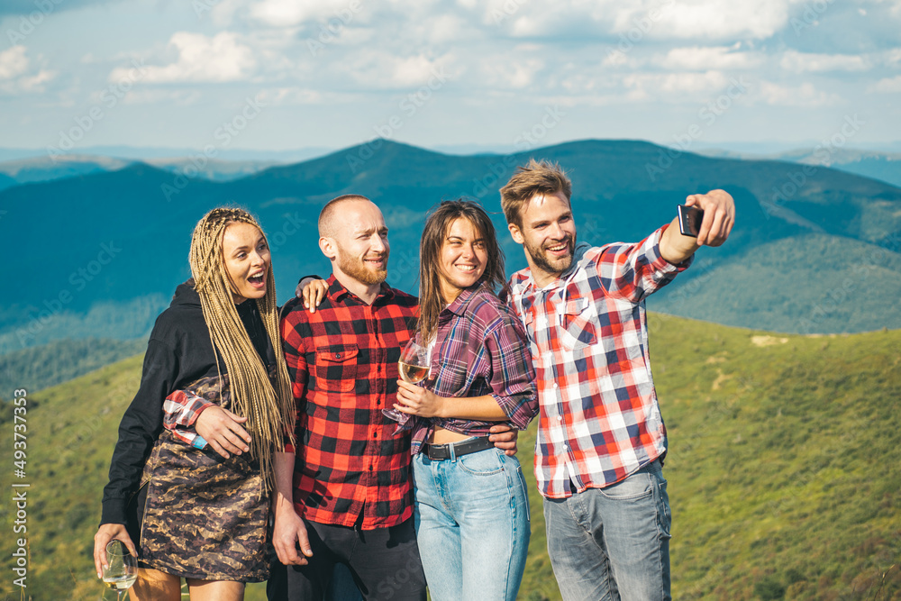 Group of friends taking a selfie in the mountains. Group of hikers takes photo in nature. Camping together is fun, friendship. Students on summer vacation laughing and talking.