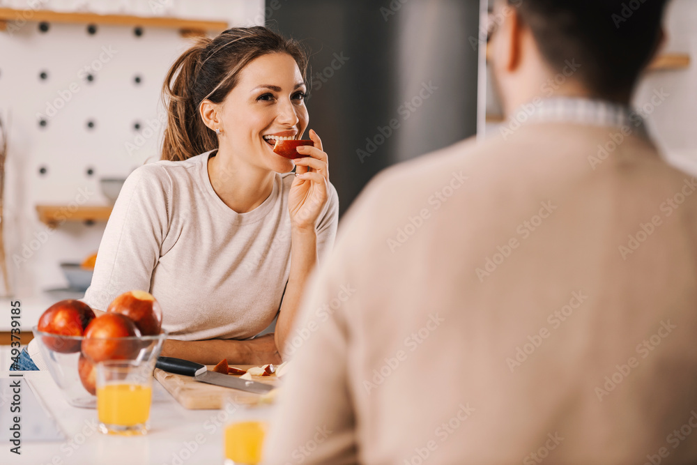 A woman having apple for a healthy snack at home and looking at boyfriend. A woman having apple for a healthy snack at home and looking at boyfriend.