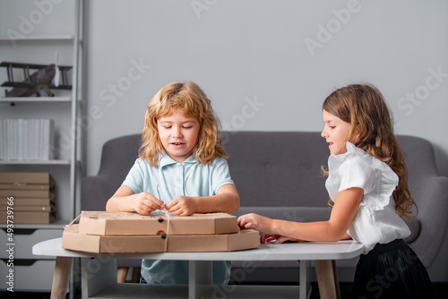 Children open pizza box at home. Funny kids boy and girl preparing to eat pizza.