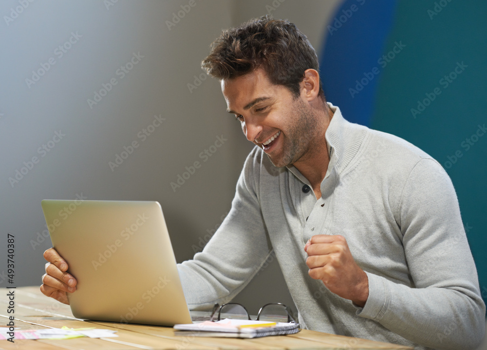 Celebrating a successful startup. A smiling entrepreneur using his laptop at a table. Celebrating a successful startup. A smiling entrepreneur using his laptop at a table.