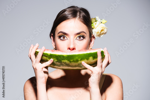 Closeup portrait of young sensual hispanic or italian woman eating watermelon isolated on gray background.