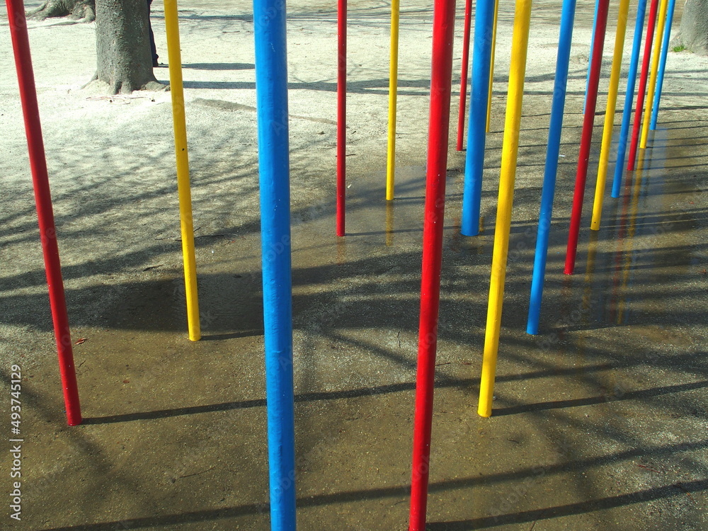 春の雨上りの公園のカラフルな上り棒の遊具