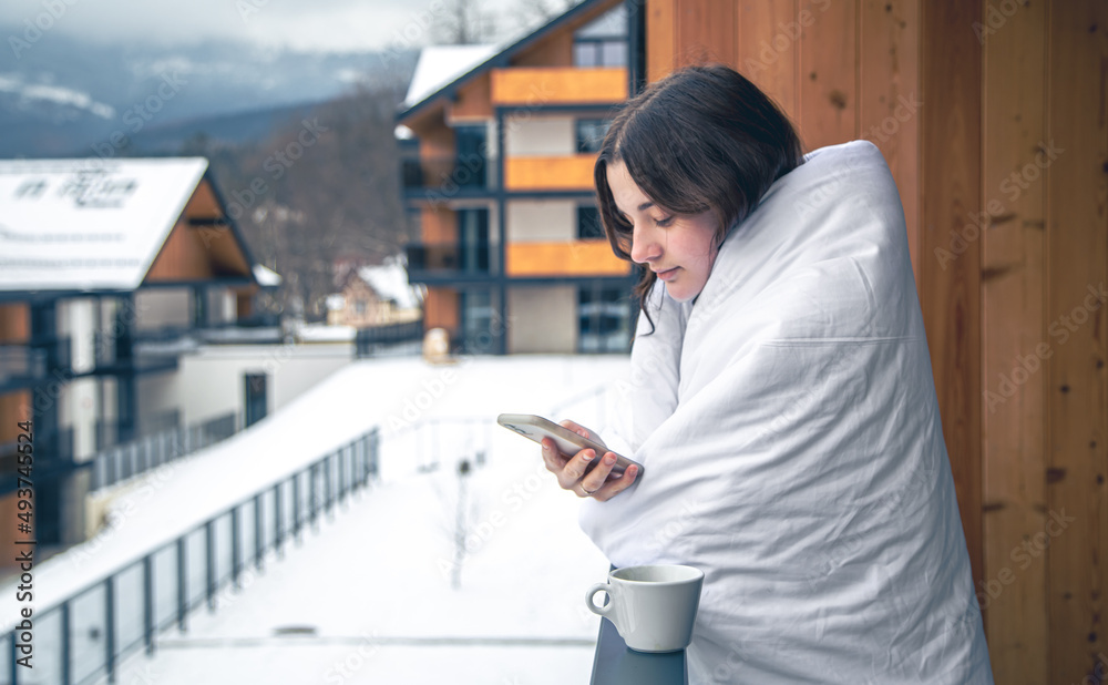 A young woman with smartphone in the mountains on the balcony of the hotel. A young woman with smartphone in the mountains on the balcony of the hotel.