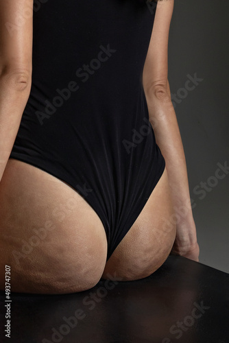 health, people, body care and beauty concept - closeup of female buttocks with cellulite on gray background