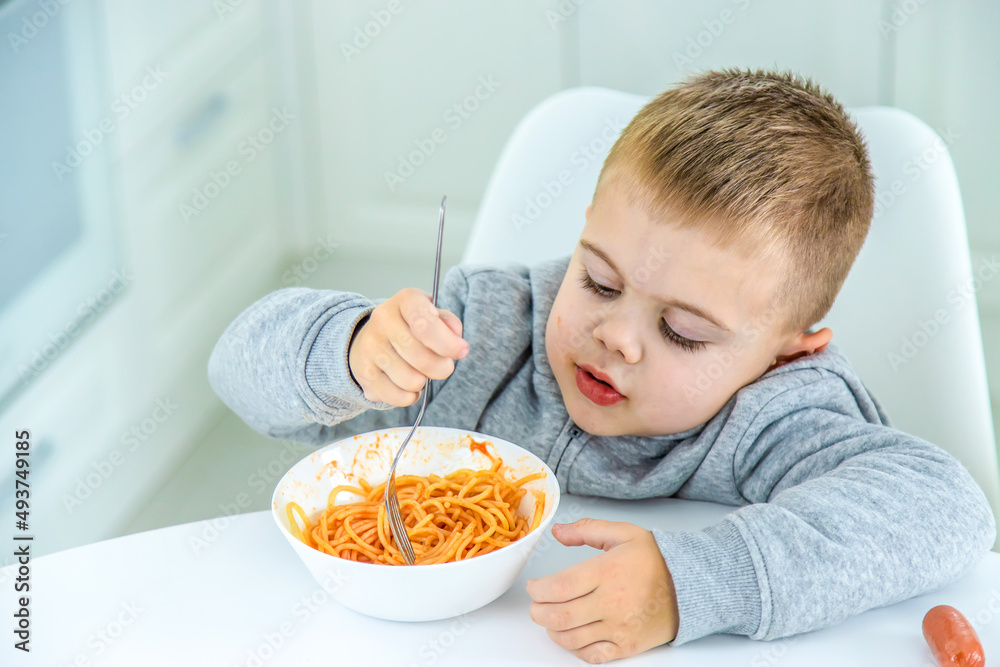 children in the kitchen at the table turning pasta. children in the kitchen at the table turning pasta.