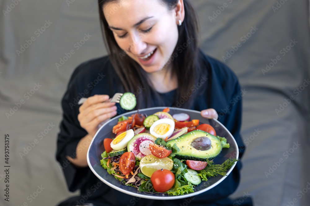 Appetizing salad with fresh vegetables and eggs in a plate in female hands.