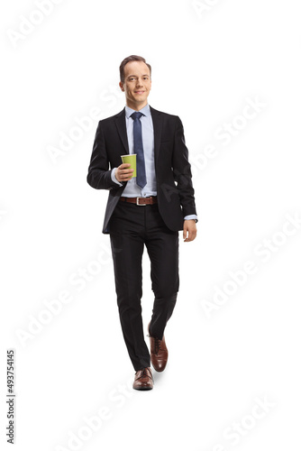 Full length portrait of a businessman walking towards camera with a cup of takeaway coffee