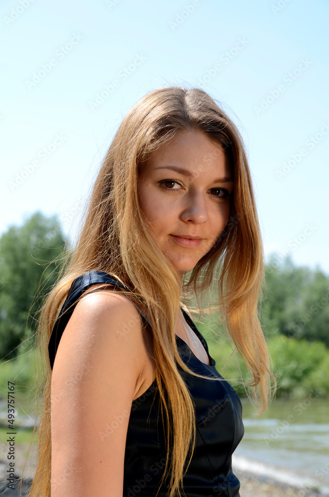 junges hübsches Mädchen in blauen Minikleid an Flussufer im Sommer