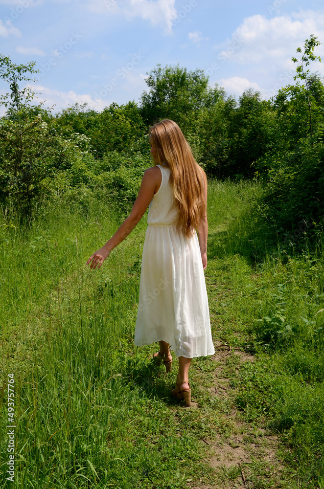 junges hübsches Mädchen im Grünen im langen Kleid