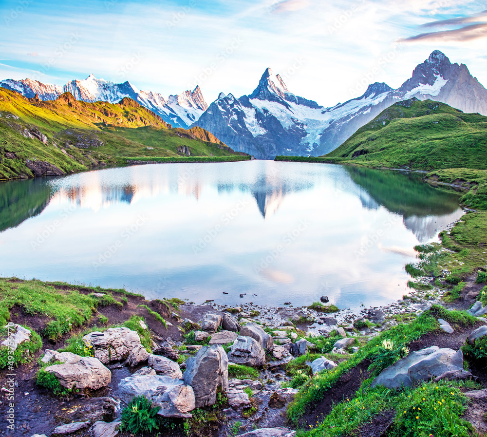 Fantastic landscape at sunrise with stones in the foreground on the lake in the Swiss Alps. Wetterhorn, Schreckhorn, Finsteraarhorn et Bachsee. Exciting places. (relaxation, harmony - concept).