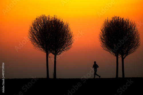 silhouette of runner against orange sky during sunset
