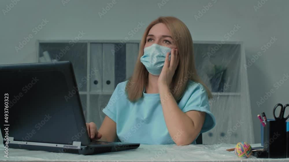 Stressed tired young woman wear face mask using laptop working overtime at office. Overload at night, social distancing. Stressed tired young woman wear face mask using laptop working overtime at office. Overload at night, social distancing.