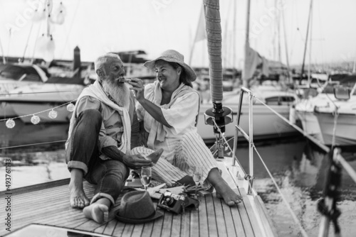Senior couple having fun eating fruits on sail boat - Focus on woman face - Black and white edition