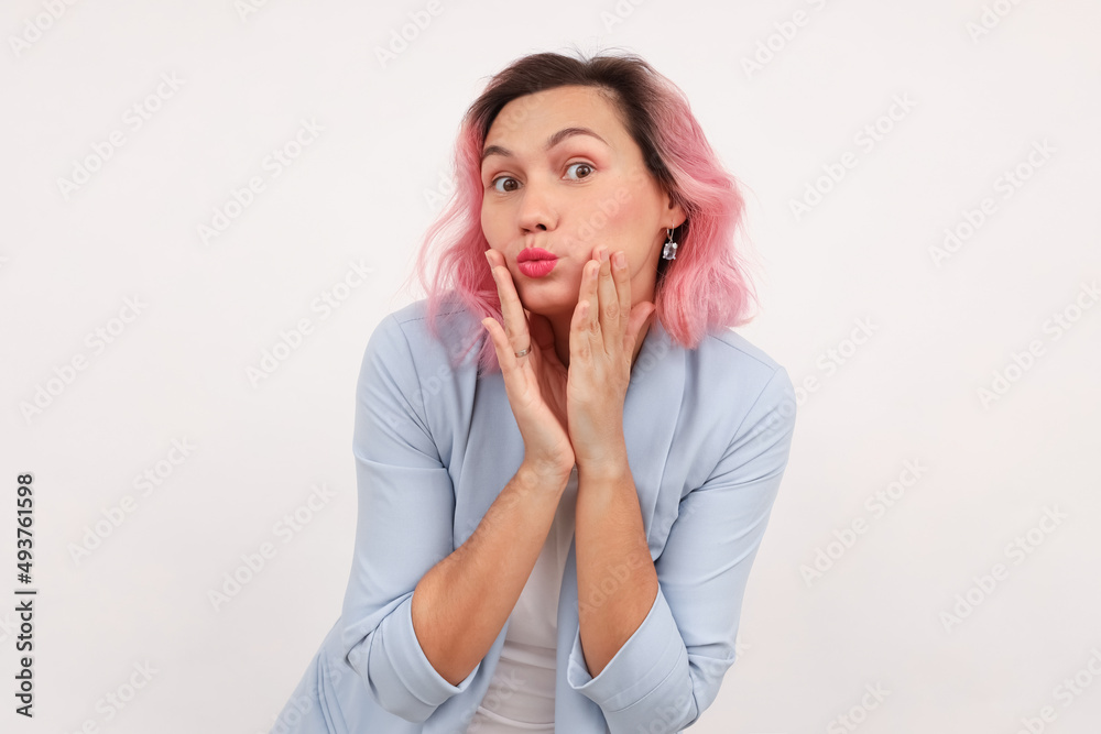 a young woman looks at the camera with interest and surprise, raising her eyebrows and looking silly, standing on a white background. a young woman looks at the camera with interest and surprise, raising her eyebrows and looking silly, standing on a white background.