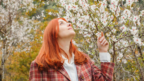 Happy red-haired girl under spring flower tree. Spring mood.
