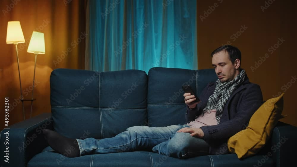 Cheerful man on the sofa using phone smile in the modern apartment texting message scrolling tapping technology isolated lifestyle Cheerful man on the sofa using phone smile in the modern apartment texting message scrolling tapping technology isolated lifestyle