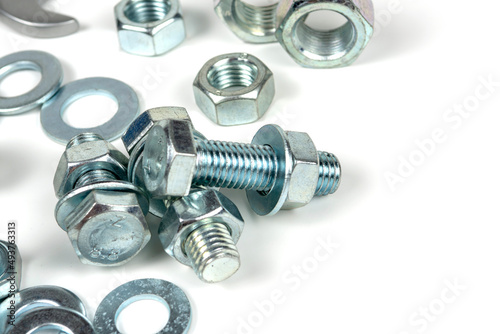 Several silver metal mounting bolts with nuts and washers on a white background. Close-up. copy space