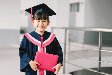 Portrait of a cute Asian graduated schoolgirl with graduation gown in school