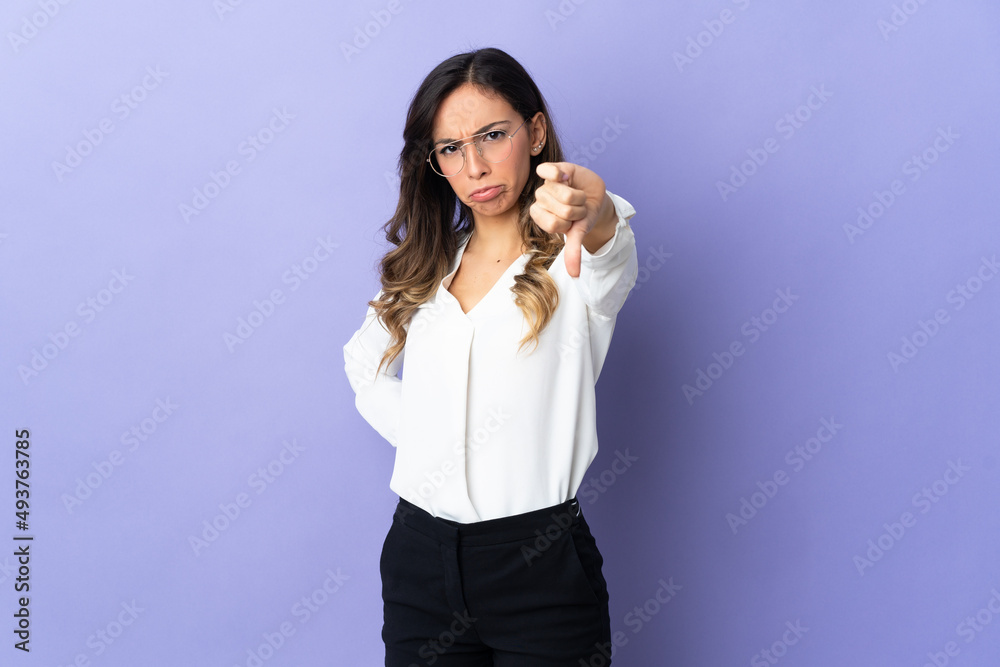 Young caucasian woman isolated on purple background showing thumb down with negative expression Young caucasian woman isolated on purple background showing thumb down with negative expression