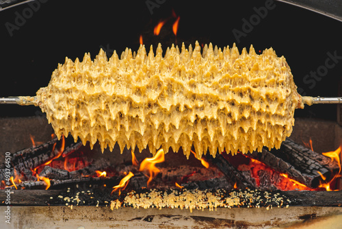 Preparing on an open fire and flames Sakotis, Lithuanian or Polish traditional cuisine layered cake, biscuit or sweet, holiday event food photo