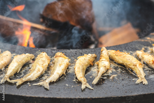 Preparing traditional tasty fried fish being cooked on an open fire in a street food market, ready to eat, street food in Vilnius, Lithuania, close up
