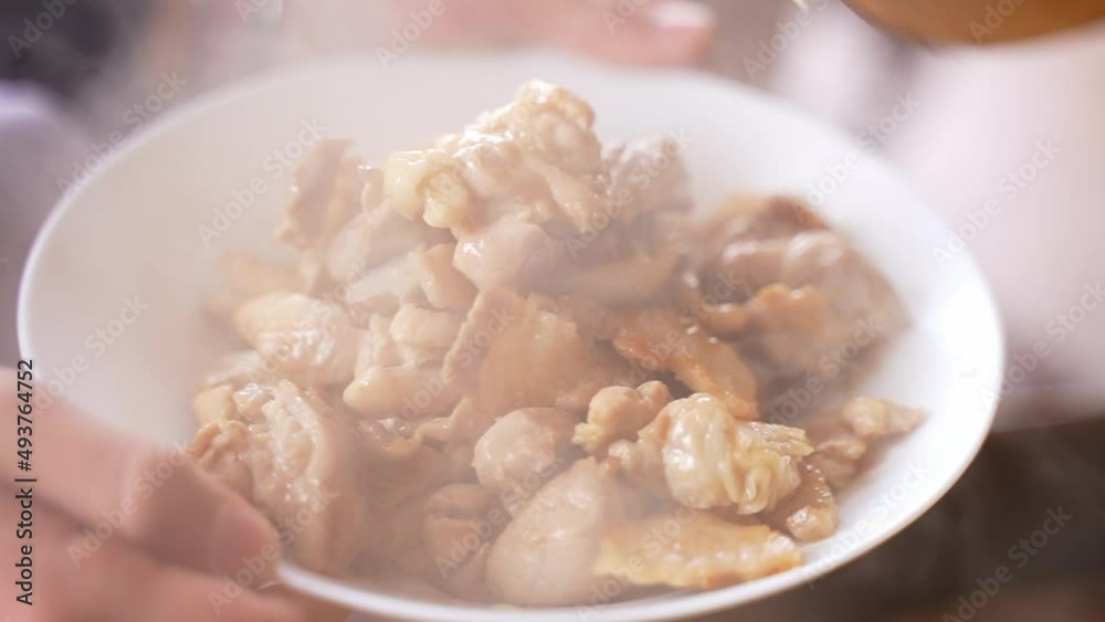Waiter or chef puts pieces of pork meat in a white plate at the restaurant. Waiter or chef puts pieces of pork meat in a white plate at the restaurant.