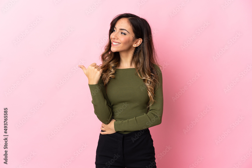 Young caucasian woman isolated on pink background pointing to the side to present a product Young caucasian woman isolated on pink background pointing to the side to present a product