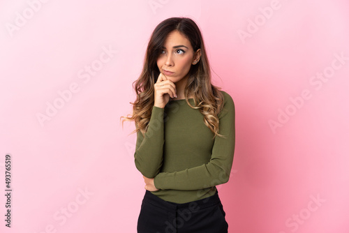 Young caucasian woman isolated on pink background having doubts and thinking © luismolinero