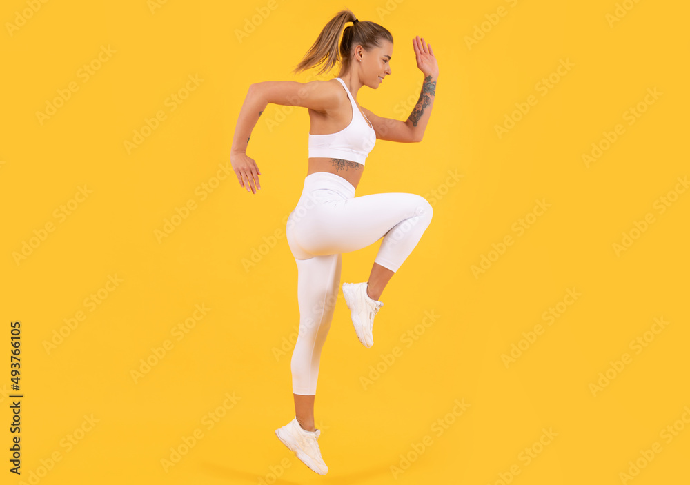 fitness coach woman jumping on yellow background