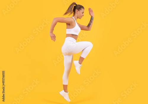 fitness coach woman jumping on yellow background
