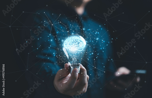 Businessman hand holding lightbulb with glowing virtual brain and  connection line to creative smart thinking for inspiration and innovation with network concept. photo